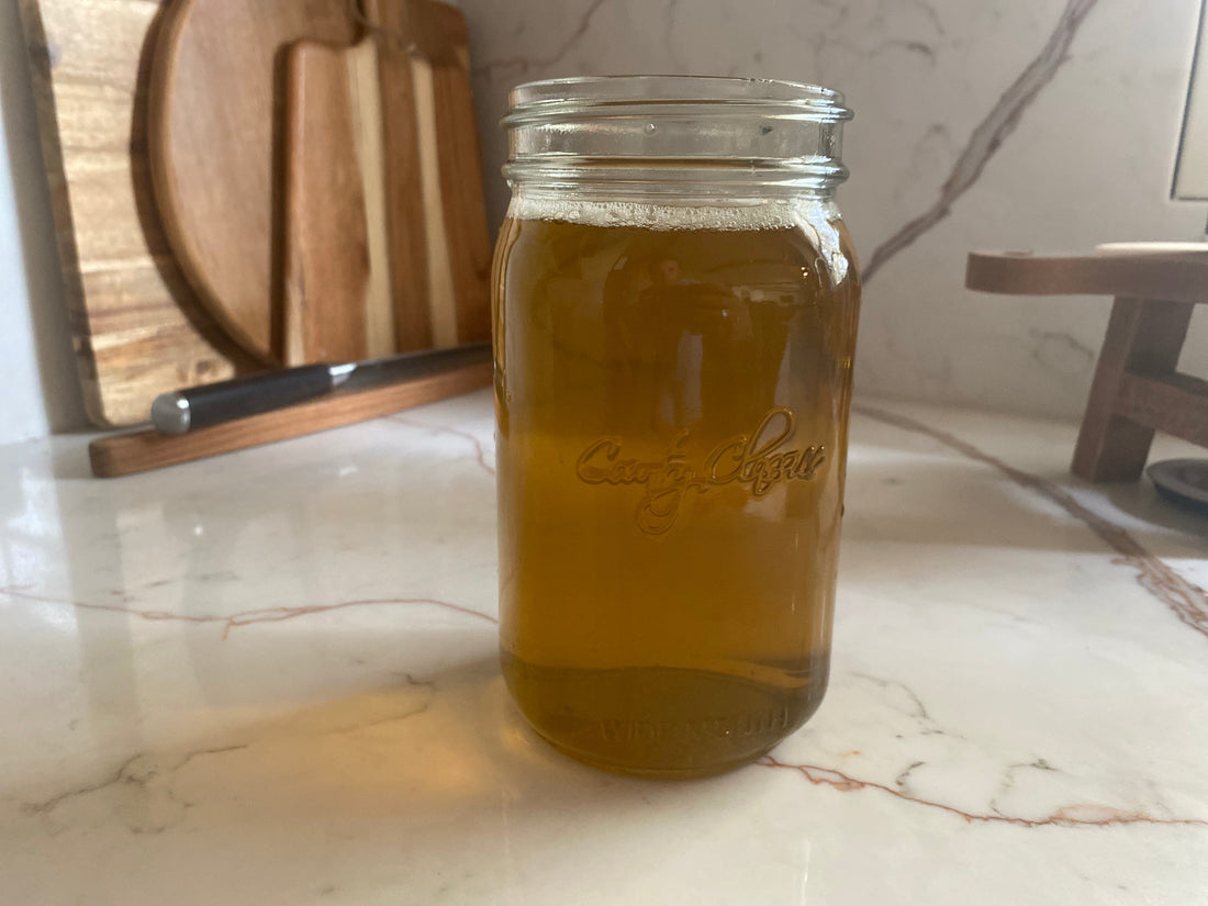 Homemade vegetable stock strained and stored in a mason jar